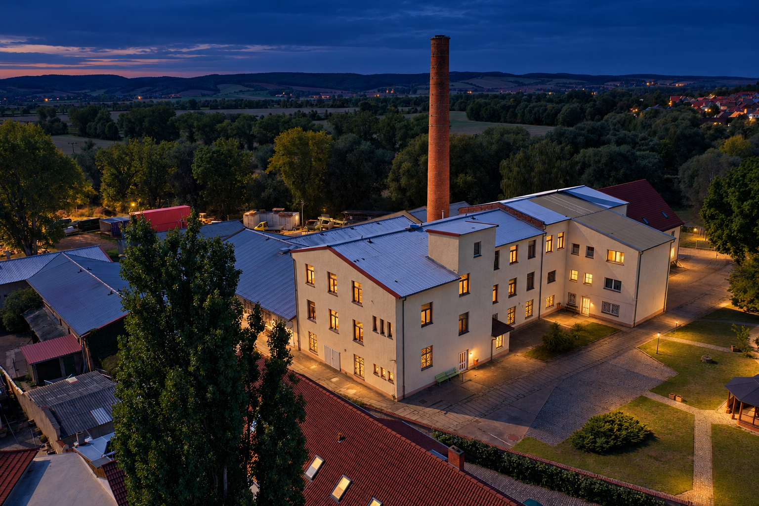 Konzeptionelle Lichtstudie der bestehenden Schuhfabrik zur blauen Stunde; KI-Visualisierung auf Basis des Originalfotos